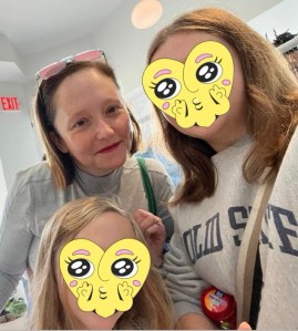 The female author of this piece with her two daughters. The daughters have smiley face hearts over their faces.